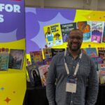 Author standing at a colorful booth at a conference