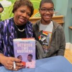 Author and child smiling as author holds a book
